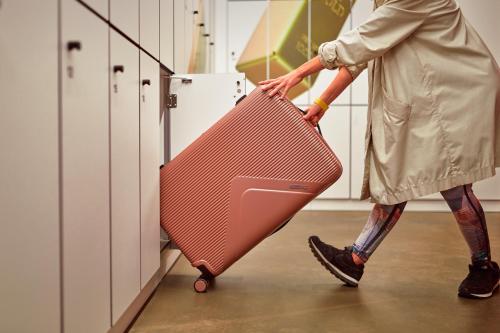 a woman is pulling a pink suitcase in a kitchen at CityHub Copenhagen in Copenhagen