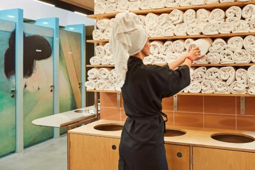 a woman with a towel on her head looking at a shelf of towels at CityHub Copenhagen in Copenhagen