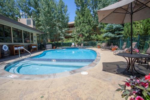 a swimming pool with a table and an umbrella at Canyon Creek in Steamboat Springs
