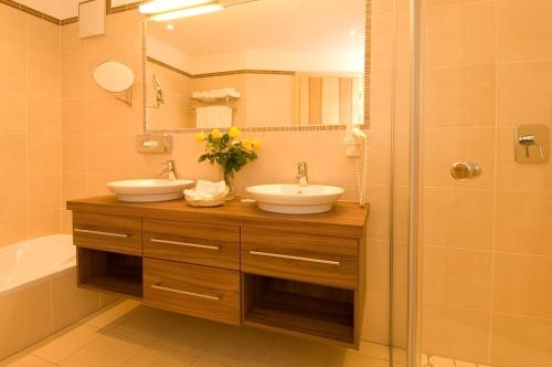 a bathroom with two sinks and a shower at Hotel Alpen Residence in Ehrwald