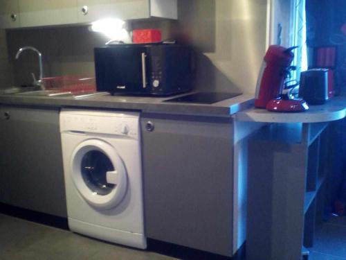 a kitchen with a washing machine and a sink at Joli petit T4 confortable au bord de leau in Vieille-Brioude