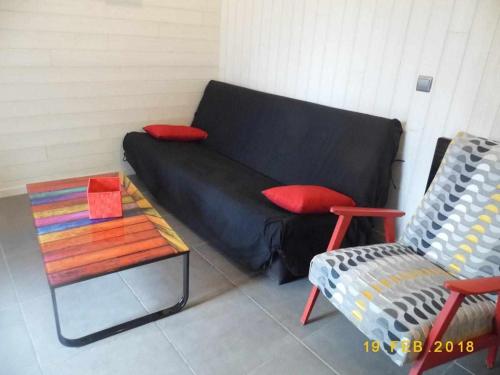 a black couch in a room with a table and a chair at Joli petit T4 confortable au bord de leau in Vieille-Brioude