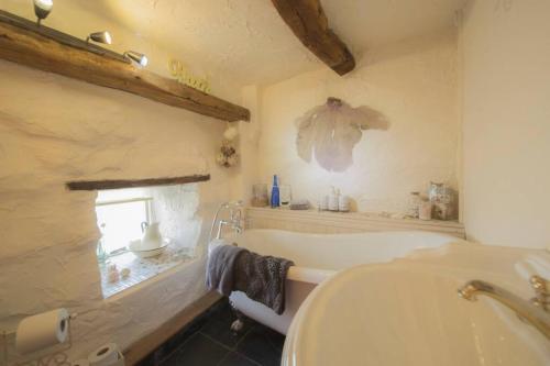 a bathroom with a tub and a sink and a window at The Bothy at Woodend with Views of Scafell in Broughton in Furness