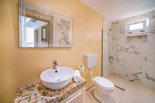 La salle de bains est pourvue d'un lavabo, de toilettes et d'un miroir. dans l'établissement Laplaya Beach, à Mália