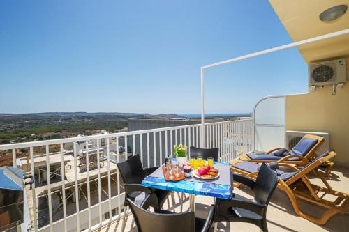 uma varanda com uma mesa e cadeiras. em Summer Breeze apartment with terrace with Panoramic views - by Getawaysmalta em Mellieħa