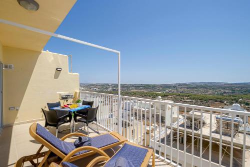 uma varanda com cadeiras e uma mesa com vista em Summer Breeze apartment with terrace with Panoramic views - by Getawaysmalta em Mellieħa