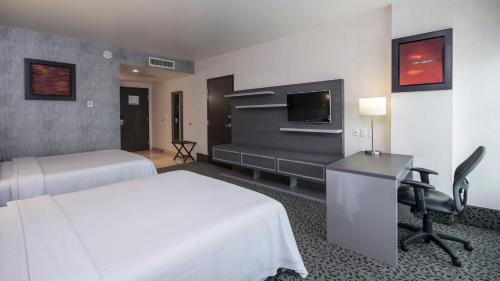 a hotel room with two beds and a desk and a tv at Holiday Inn Express & Suites Queretaro by IHG in Querétaro