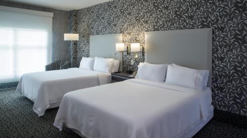 two beds in a hotel room with white sheets at Holiday Inn Express & Suites Queretaro by IHG in Querétaro