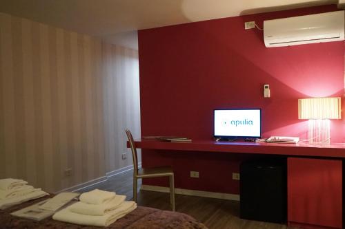 een kamer met een bureau met een computer op een rode muur bij Dante's Room by Apulia Accommodation in Bari