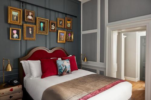 a bedroom with a bed with red pillows and pictures on the wall at Hotel Indigo - Bath, an IHG Hotel in Bath
