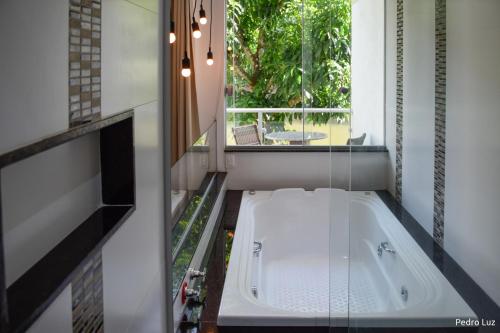 a bath tub in a bathroom with a window at Pousada Valle dos Pássaros in Penedo
