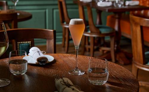 a glass of wine sitting on a table with glasses at Hotel Indigo - Bath by IHG in Bath