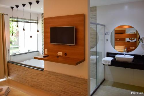 a bathroom with a television on a wall and a sink at Pousada Valle dos Pássaros in Penedo