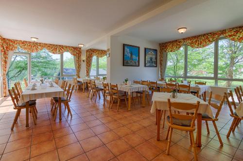 a dining room with tables and chairs and windows at Hotel Haus Oberland in Masserberg