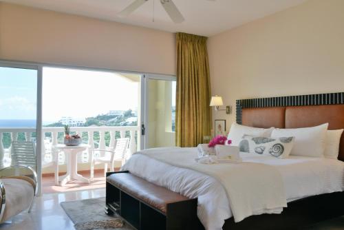 a bedroom with a large bed and a balcony at Princess Heights Luxury Condo Hotel in Dawn Beach