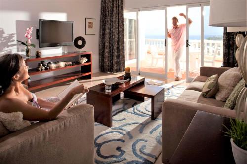 a woman sitting on a couch in a living room at Princess Heights Luxury Condo Hotel in Dawn Beach