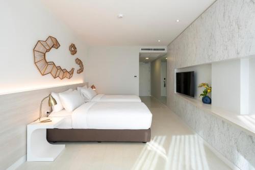 a white bedroom with a bed and a tv at VELA Dhi Udon Thani in Udon Thani