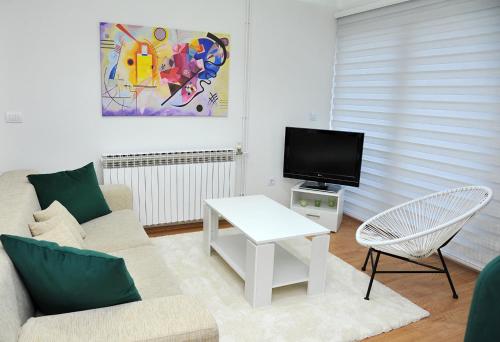 ein Wohnzimmer mit einem Sofa und einem TV in der Unterkunft Apartman Lizdek in Pale