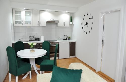a kitchen with a table and green chairs in a room at Apartman Lizdek in Pale