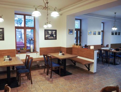 un restaurante con mesas y sillas de madera y ventanas en Hotel Sýkora, en Křivoklát