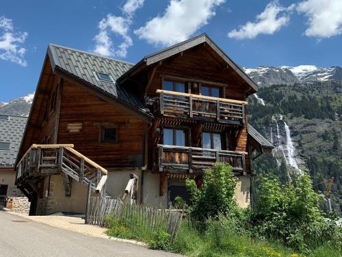 a large wooden house with mountains in the background at VAUJANYLOCATIONS - Le Grenier de Germaine in Vaujany