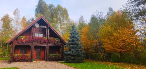 una pequeña casa con flores frente a un bosque en Lakeside Cottage, en Sajzy