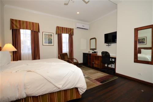 1 dormitorio con cama, escritorio y espejo en Cara Lodge Hotel, en Georgetown