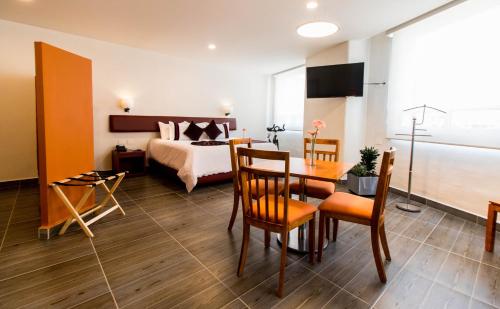 um quarto de hotel com uma cama, uma mesa e cadeiras em Mision Puebla Angelopolis em Puebla