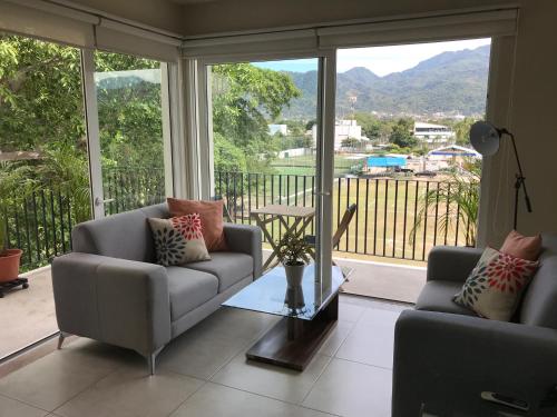 a living room with two couches and a large window at Departamento con espectacular vista a la montaña. in Puerto Vallarta