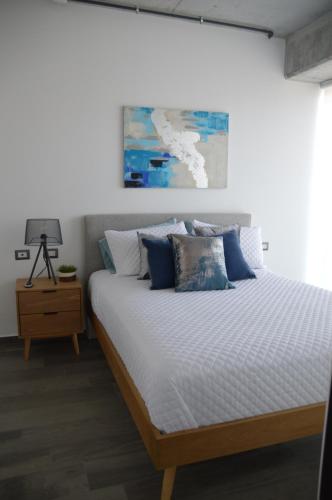 a bedroom with a large bed with blue pillows at Cozy Stays Cayala Apartments 3 in Guatemala