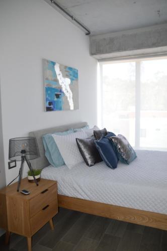 a bedroom with a bed with pillows and a window at Cozy Stays Cayala Apartments 3 in Guatemala