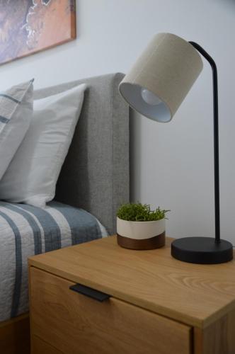 a lamp on a night stand next to a bed at Cozy Stays Cayala Apartments 3 in Guatemala