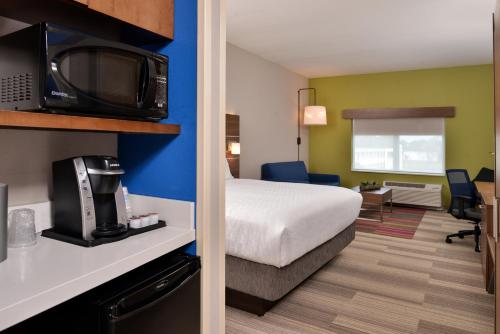 a hotel room with a bed and a tv and a room at Holiday Inn Express & Suites Alachua - Gainesville Area by IHG in Alachua