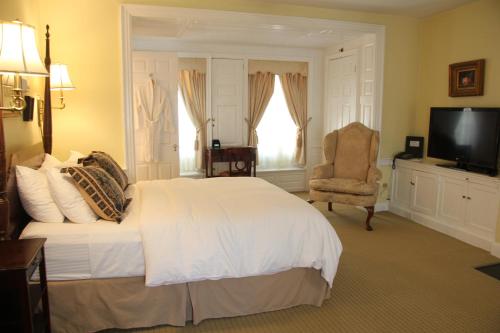 a bedroom with a white bed and a chair and a television at Morris House Hotel in Philadelphia