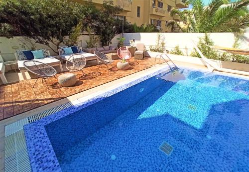 a large swimming pool with chairs and a table at Hotel Parthenon Rodos city in Rhodes Town