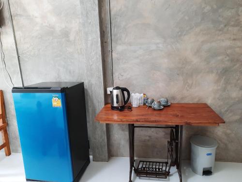 a table with a blue refrigerator and a table with a tv at Pottery Street House in Sukhothai