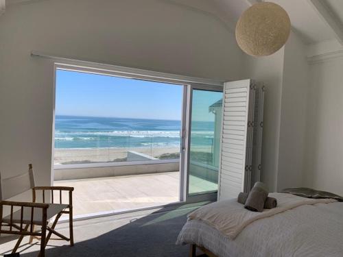 a bedroom with a bed and a view of the ocean at 9 on the beach in St Helena Bay
