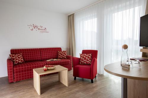 a living room with a red couch and a table at Kohlers Hotel Engel in Bühl