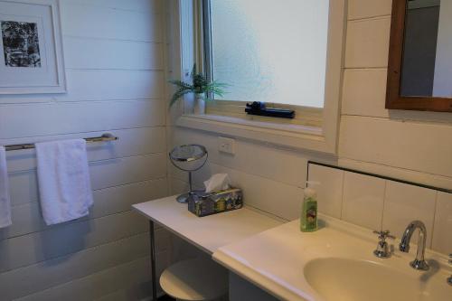 a bathroom with a sink and a toilet and a window at BINALONG BEACH COTTAGE Beachfront at Bay of Fires Next to Restaurant in Binalong Bay