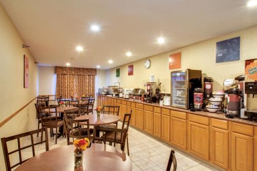 a restaurant with tables and chairs and a counter at Baymont by Wyndham Fort Dodge in Fort Dodge