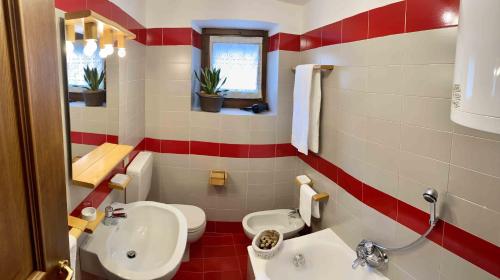 a red and white bathroom with a sink and a toilet at Casa Ornella in Courmayeur