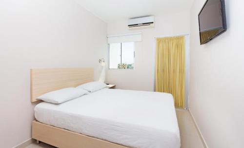 a white bedroom with a bed and a television at Ribai Hotels -Riohacha in Ríohacha