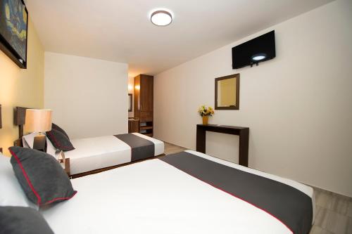 a hotel room with two beds and a television at Hotel Quinta Las Fuentes Bernal in Bernal