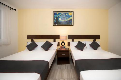two twin beds in a room with a night stand at Hotel Quinta Las Fuentes Bernal in Bernal
