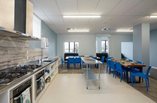 a kitchen with a table and blue chairs in it at Wanderlust NZ in Tauranga