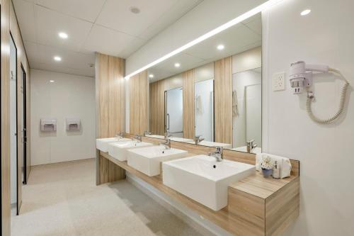 a bathroom with three sinks and a large mirror at Wanderlust NZ in Tauranga