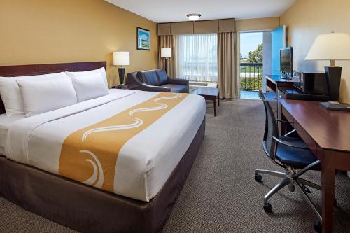 Cette chambre comprend un grand lit et un bureau. dans l'établissement Comfort Inn Encinitas Near Legoland, à Encinitas