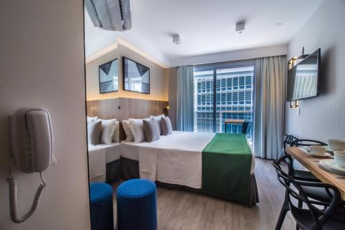 サンパウロにある360 São Luisのベッドとテーブルと机があるホテルの部屋