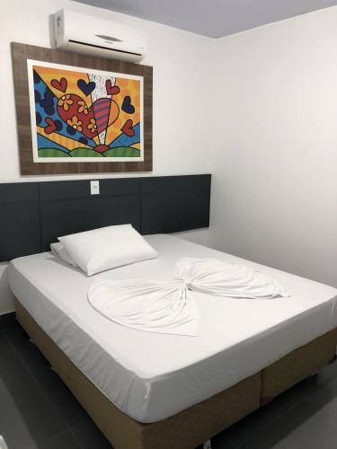a bed in a room with a painting on the wall at Residencial Flat Debora in Florianópolis