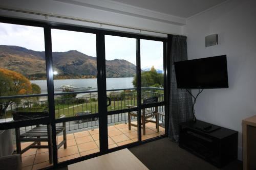 a room with a balcony with a view of a lake at The Moorings Motel and Apartments in Wanaka